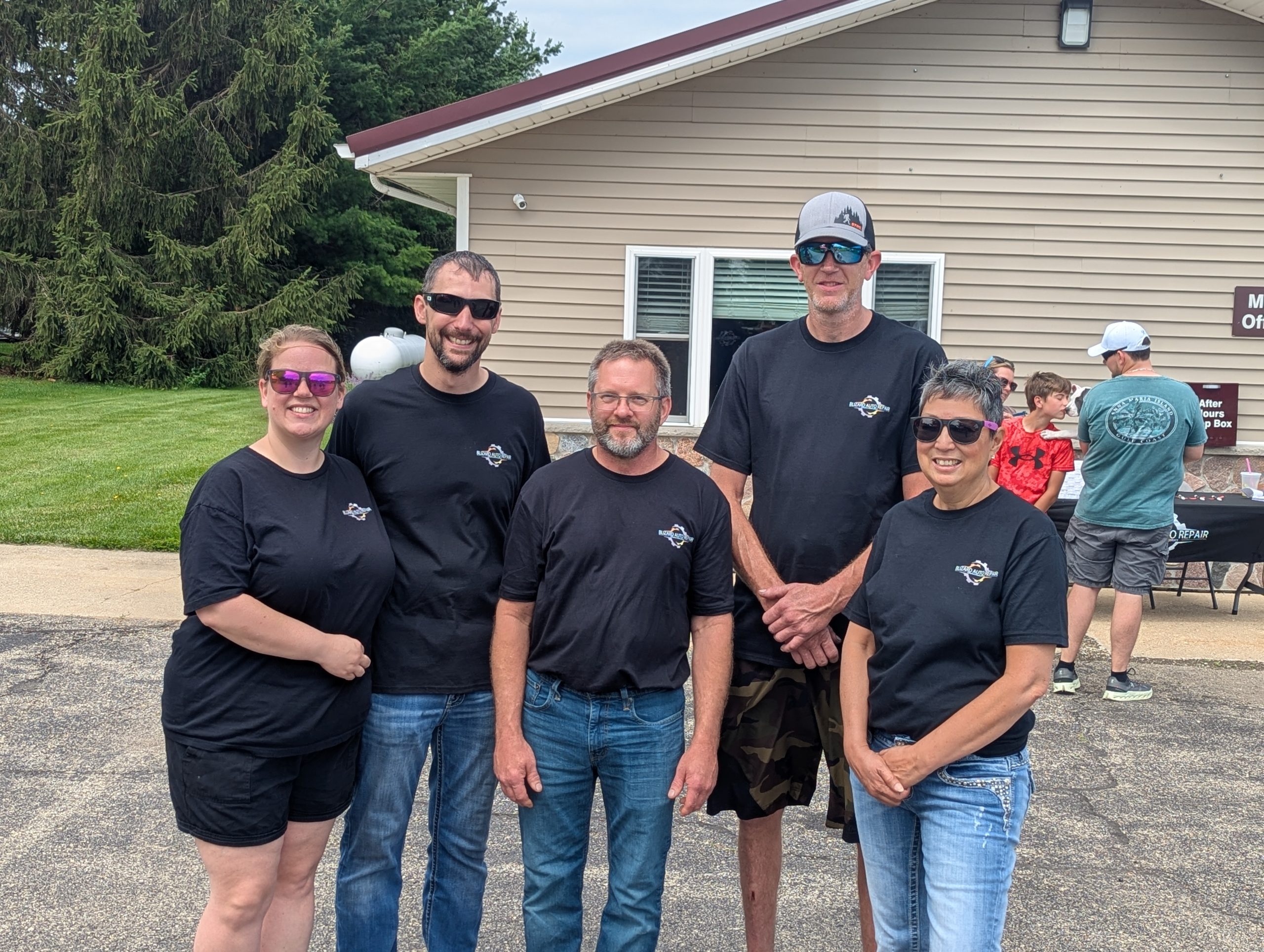The Blizard Auto Repair team of five auto technicians standing shoulder-to-shoulder inside a well-lit auto shop.